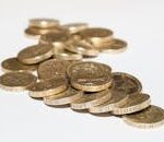 Close-up of assorted British pound coins scattered on a white surface, highlighting financial themes.